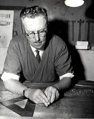 1965 photograph of Art and Architecture. Alfred Dunn preparing a metal engraving of the campus map. Donor: Publications Dept.
