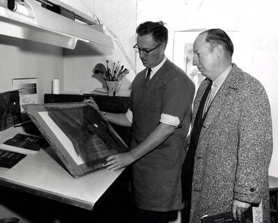 1962 photograph of Art and Architecture. Alfred Dunn showing a dust jacket to Rafe Gibbs Donor: Publications Dept.