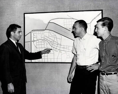 1963 photograph of Art and Architecture. Paul Blanton with students Terry Schofield and Lorenzo Nelson looking at a map. Donor: Publications Dept.