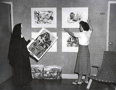 1936 photograph of Art and Architecture. Students hang paintings for an exhibit. Donor: Publications Dept.