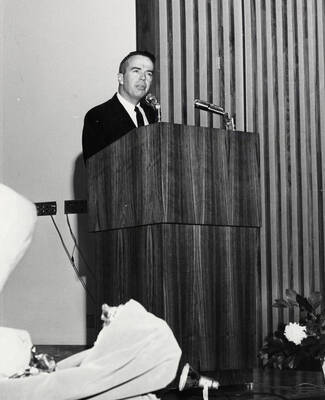 1964 photograph of 75th Anniversary. Alumni Association president James H. Roper giving a speech at a lectern.