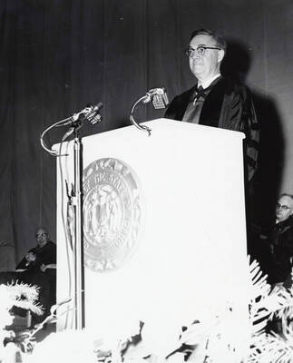 1964 photograph of 75th Anniversary. Dr. L.H. Chamberlain giving convocation address at a lectern.
