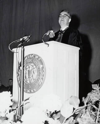 1964 photograph of 75th Anniversary. Dr. L.H. Chamberlain giving convocation address from a lectern.