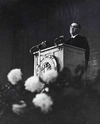1964 photograph of 75th Anniversary. Dr. L.H. Chamberlain giving convocation address from a lectern.