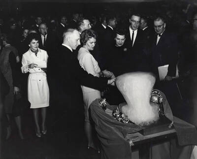 1964 photograph of 75th Anniversary. Faculty looking at an ice sculpture during the 75th Anniversary.