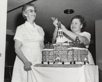 1964 photograph of 75th Anniversary. Marie Bippes and Mrs. Leroy Zeller decorate cake for the 75th Anniversary.