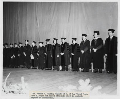 1964 photograph of 75th Anniversary. Governor Robert E. Smylie, the Regents of the U of I, Alumni President John H. Roper and other school officials in academic regalia during the convocation.