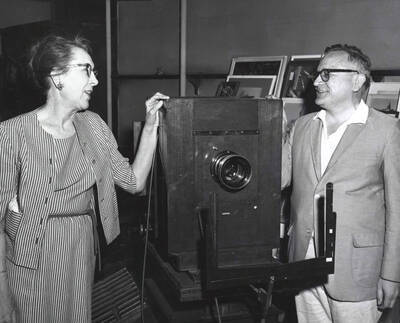 1965 photograph of Gifts. Charles Webbert and Ruth Ray examine a wooden camera