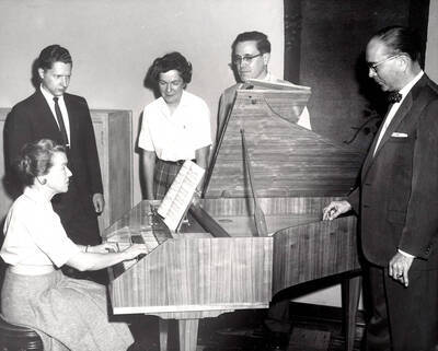 1952 photograph of Gifts. l-r: Agnes Schuldt, Steven Romanio, Marian Frykman, Bruce Bray, and Hall Macklin gathered around a harpsichord. Donor: Publications Dept.