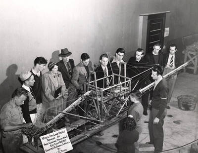 1940 photograph of Gifts. People examining a model of a dry-land dredge. Design by Fred Cushing Moore.