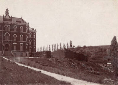 1905 photograph of Administration Building. View of the drive up to the old Administration with firewood to the right.