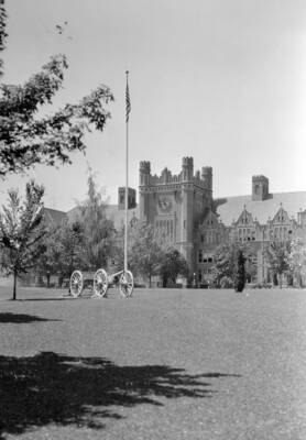 1950 photograph of Administration Building. View of the lawn, with cannon and flag centered.