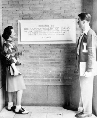1935 photograph of Administration Building. Students stand at the entrance to the Administration and the dedicatory plaque.