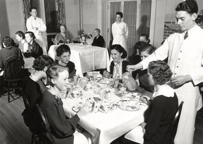 1936 photograph of Hays Hall. View of the women in their dining room along with servers.