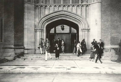 1930 photograph of University of Idaho campus scene. View of students at the building entrance.