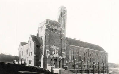 1928 photograph of Memorial Gymnasium. View of students next to building entrance.