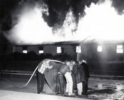 1958 photograph of Campus Club. View of students and firefighters at the fire.