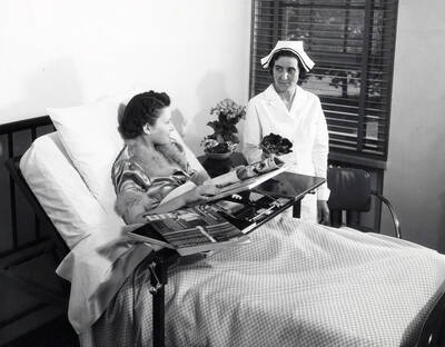 1938 photograph of Infirmary. Patient has magazines on her bed tray including a May 1938 issue of 'Life'.