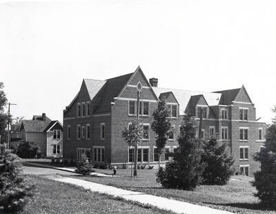 1938 photograph of Infirmary. Corner view includes the lawn, as well as parking and houses.