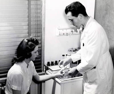 1941 photograph of Dr. Harold D. Cramer bandaging Anne Little in the Infirmary.