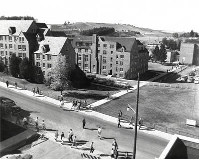 1960 photograph of Chrisman Hall. View of students walking to classes and blocked streets.