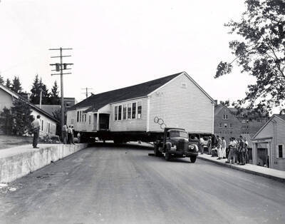 1941 photograph of Forestry Laboratory. Truck moves the building while students watch from the sidewalk.