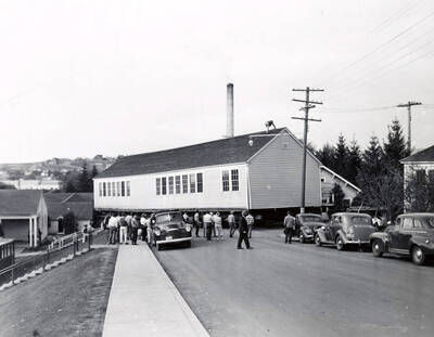 1941 photograph of Forestry Laboratory. Truck moves the building while students watch from the sidewalk.
