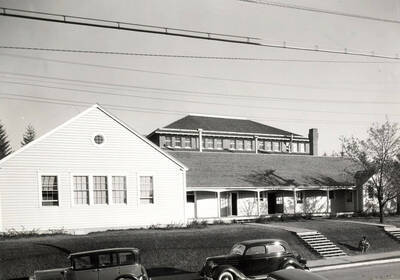 1936 photograph of University Classroom Building. Students shown sitting on the lawn.