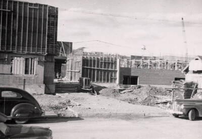 1954 photograph of Gault Hall under construction. Automobiles in foreground. Donor: Maurice Johnson.