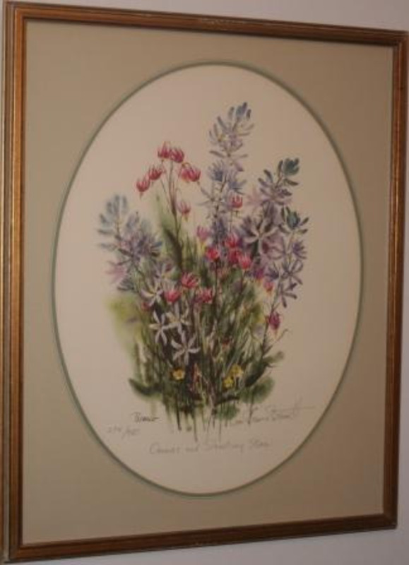 Painting of camas and shooting star wildflowers displayed in a gilt wood frame and on green oval mat.