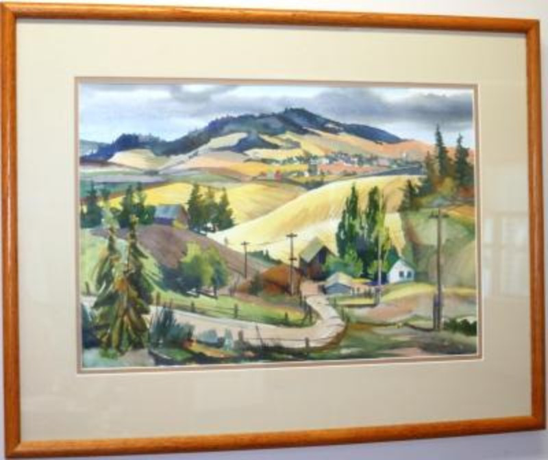 Landscape watercolor painting depicting a road that leads to a few buildings, with hilly background. Trees appear along the road and in the background. It is displayed in a light wood frame.