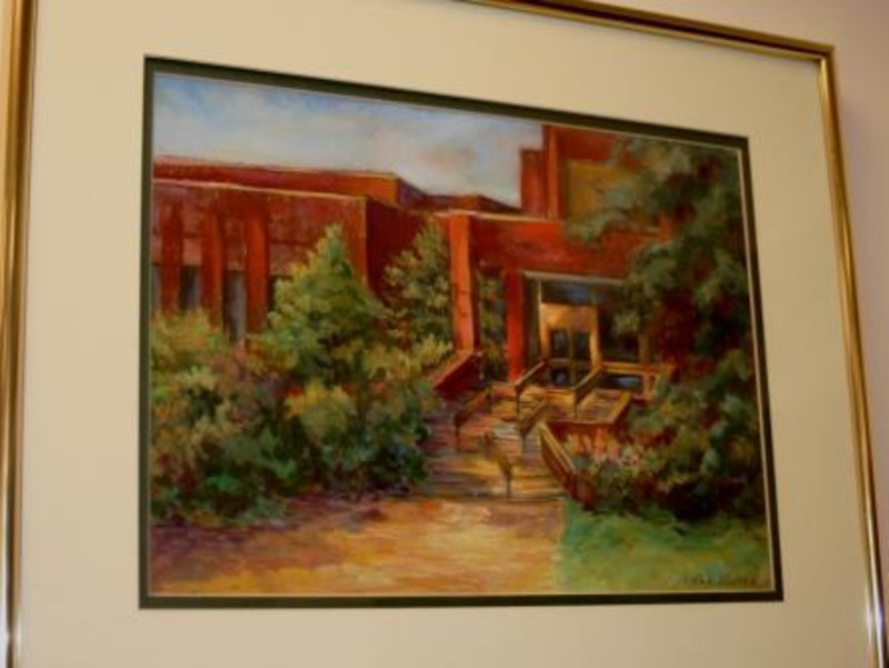 Pastel drawing of the entrance to the Menard Law Building in the spring. It is displayed in a gold frame.