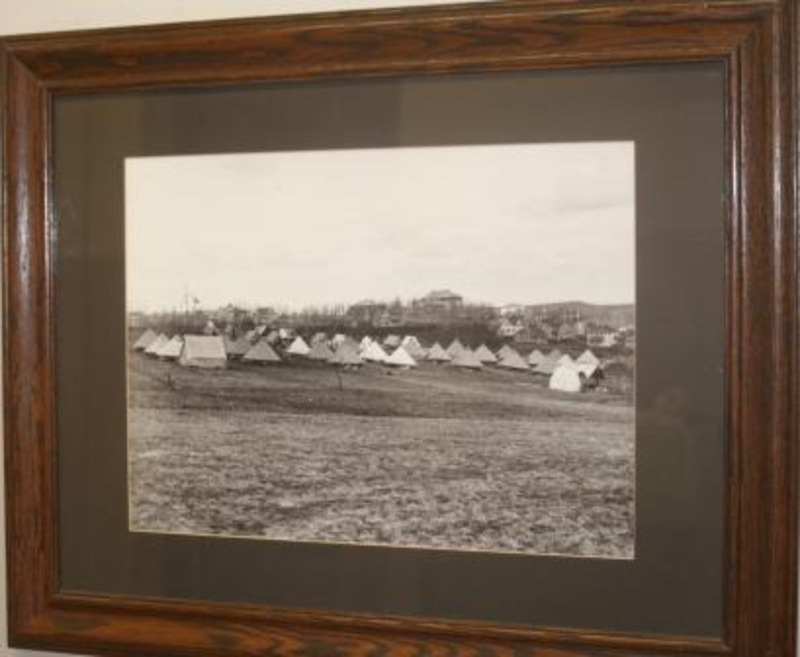 Framed black and white photograph of a military encampment under glass.