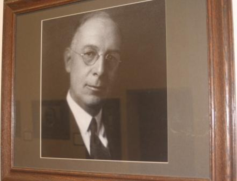 Framed black and white portrait photograph of Alfred H. Upham under glass.