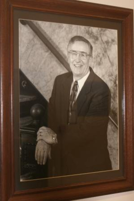 Black and white photograph of Thomas O. Bell, acting president of the University of Idaho 1995-1996. Displayed under glass in a wooden frame.