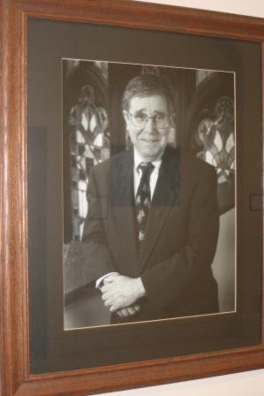 Black and white portrait photograph of Robert A. Hoover, president of the University of Idaho 1996-2003. Displayed under glass in a wooden frame.