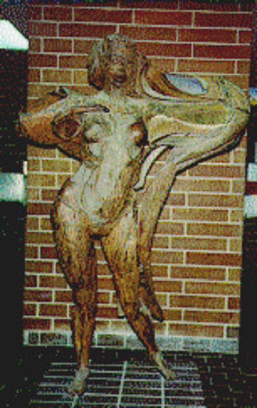 Sculpture of a feminine figure made from welded and brazed steel displayed on a  brick platform.