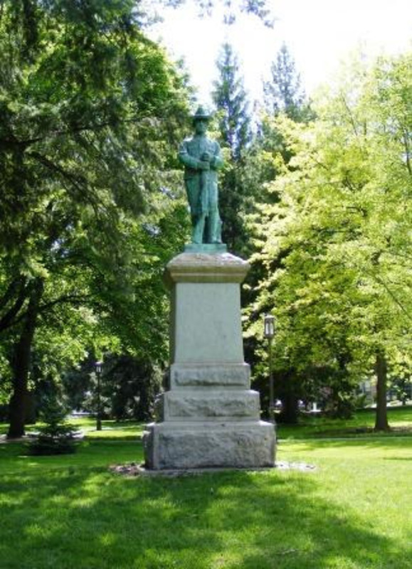 Statue of a bronze soldier holding a rifle standing on granite and concrete base.