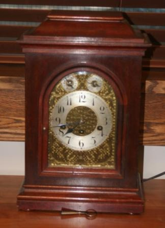 Mantle clock made from metal and wood with a German face, key in back, #9 inscription, and pencil marks.