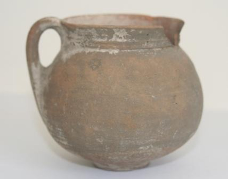 Unglazed terracotta pot with a small handle.