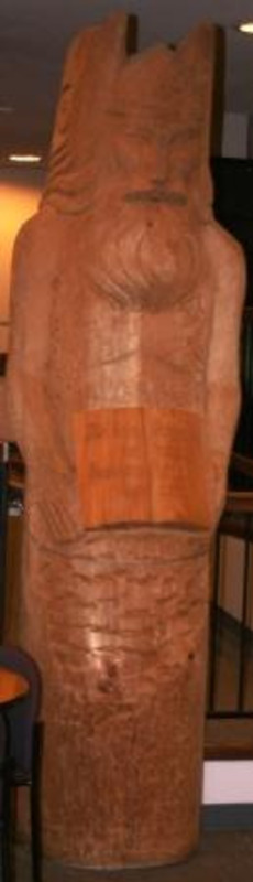 Carved wooden sculpture of a wing-helmeted vandal holding an open book. Sculpture is signed.