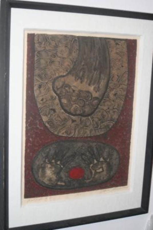 Print showing shapes and forms depicted in red, brown and black with a pair of hand prints. Displayed using a white matte in a black frame. Labeled as the first print of twenty.