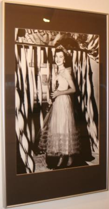Black and white photograph of Sigma Alpha Epsilon's Violet Queen standing in front of a background of ribbons.