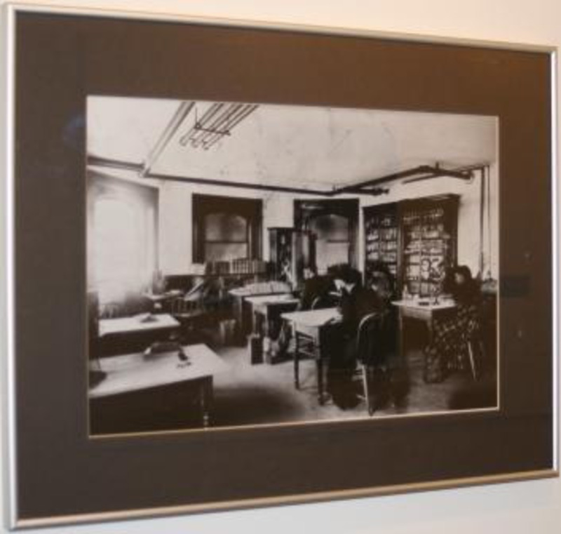 Black and white photograph  showing students sitting at desks in an old classroom.