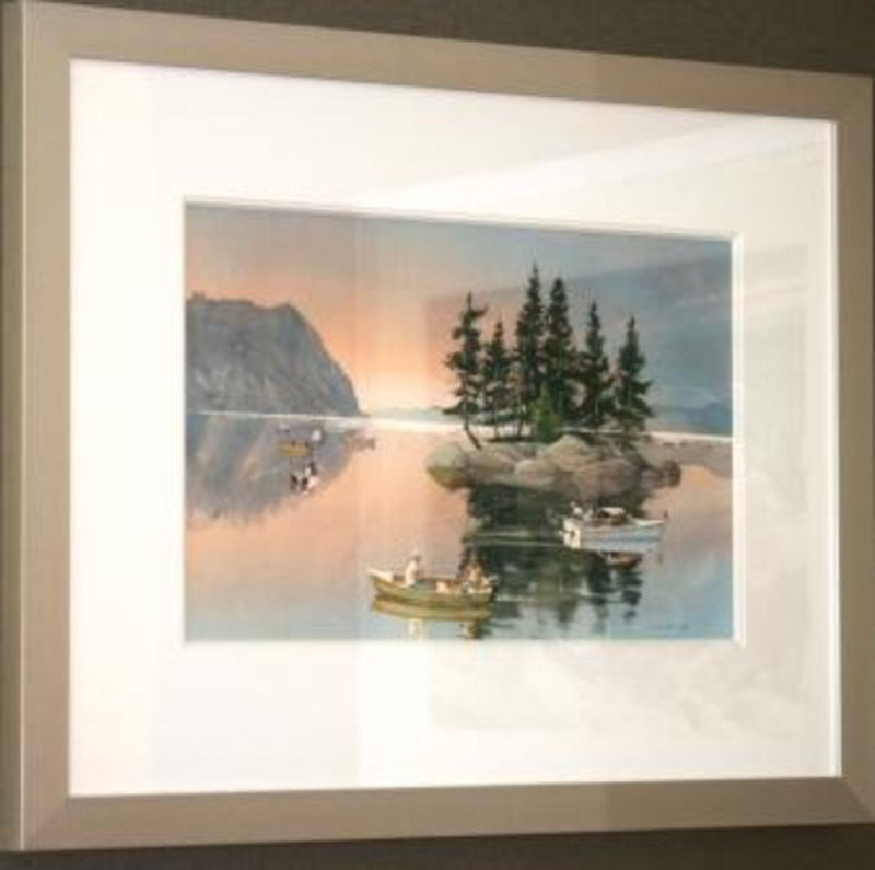 Painting depicting fishermen using boats on a still lake with a rocky, tree covered island. Displayed using a white matte in a silver frame.
