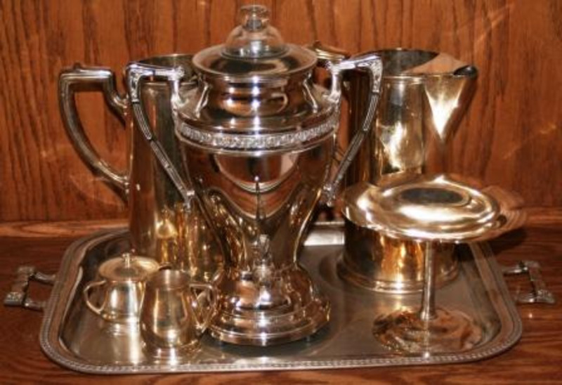 Silver tea service consisting of an urn, two pitchers, creamer, sugar container, and an elevated tray.