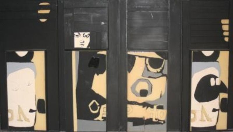 Mixed media sculpture made from four painted folding panels showing a face and several different forms made with black, white, grey, and gold paint.