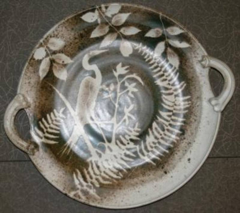Stoneware platter decorated with the image of a crane and leaves by using a stencil and iron oxide.