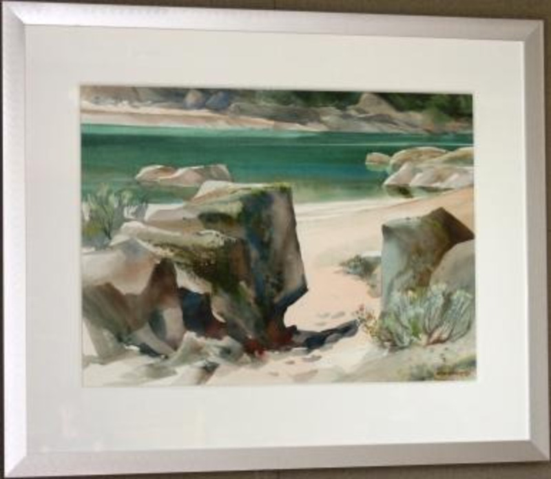 Painting of rocks and brush on a sandy lakeshore. The painting is displayed with a white matte and a silver frame.