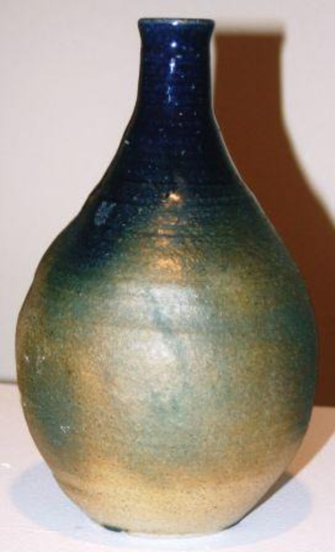 Stoneware vase that is bottle-shaped with an under-fired glaze and without much reduction during firing.